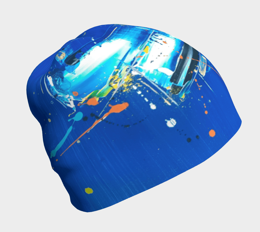 Tuque bleue ornée d'un motif abstrait dynamique aux éclaboussures blanches, jaunes et orange sur fond bleu vif.