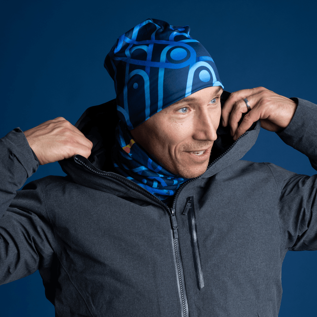 Homme portant une veste gris foncé et une tuque et un cache-cou bleus assortis.