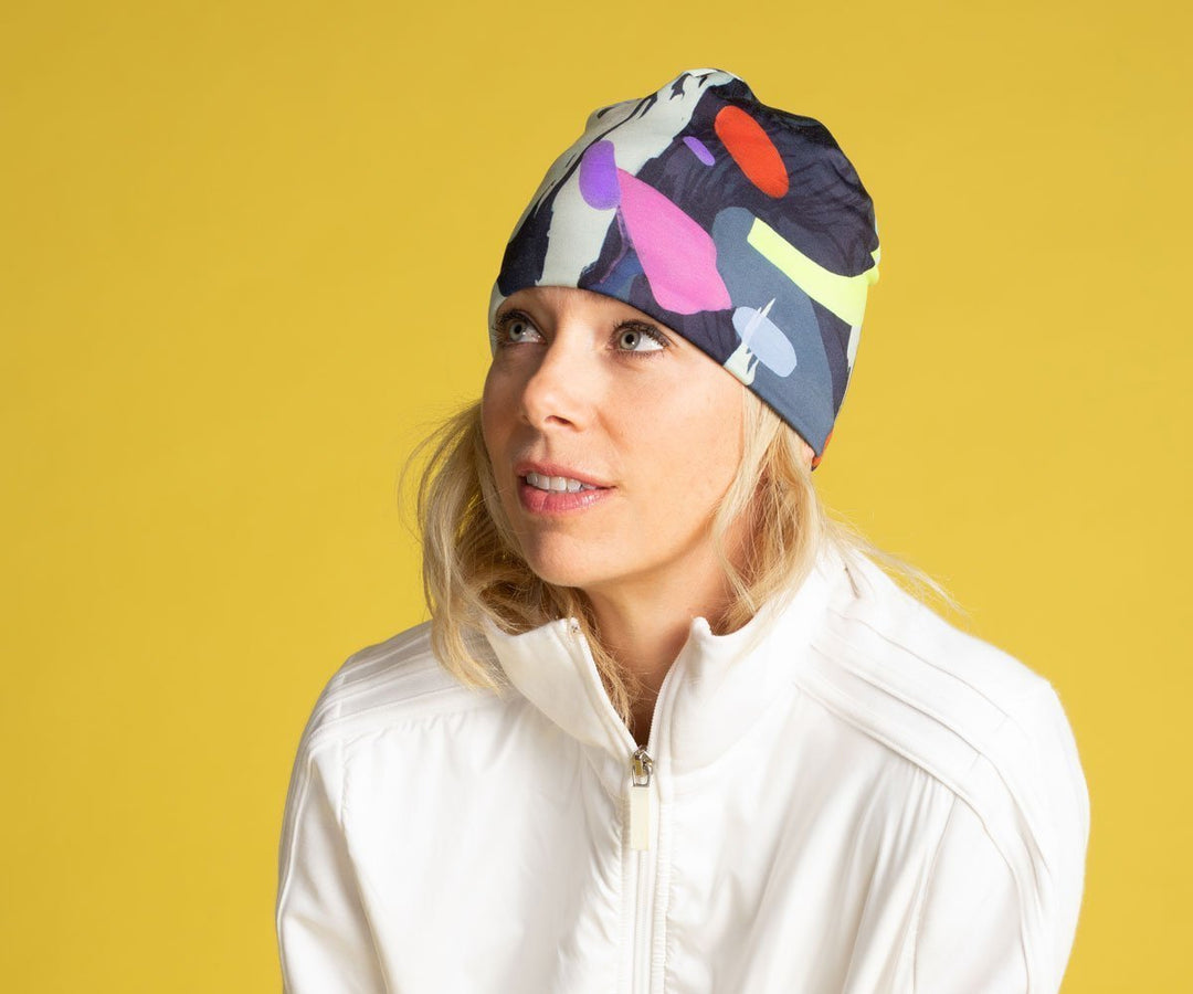 Femme portant la tuque motif corbeau abstrait avec une veste blanche