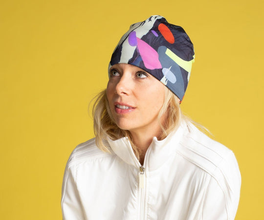 Femme portant la tuque motif corbeau abstrait avec une veste blanche