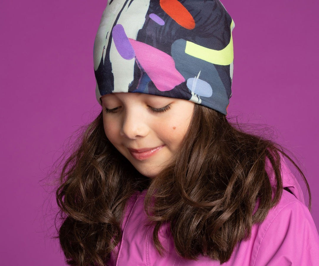 Jeune fille portant la tuque motif corbeau abstrait avec une veste rose