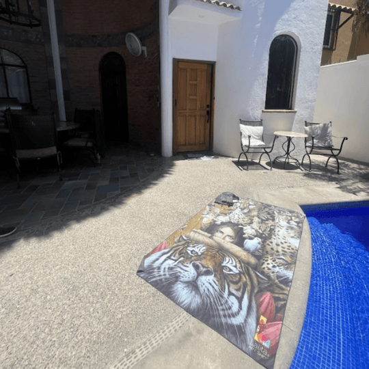 La serviette artistique réversible XL Félins drapée au bord de la piscine, présentant un tigre vibrant et une œuvre féline.