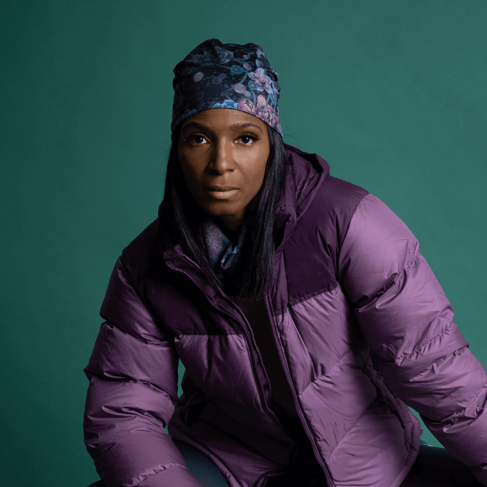 Femme portant une veste d'hiver violette et une tuque à imprimé floral foncé.
