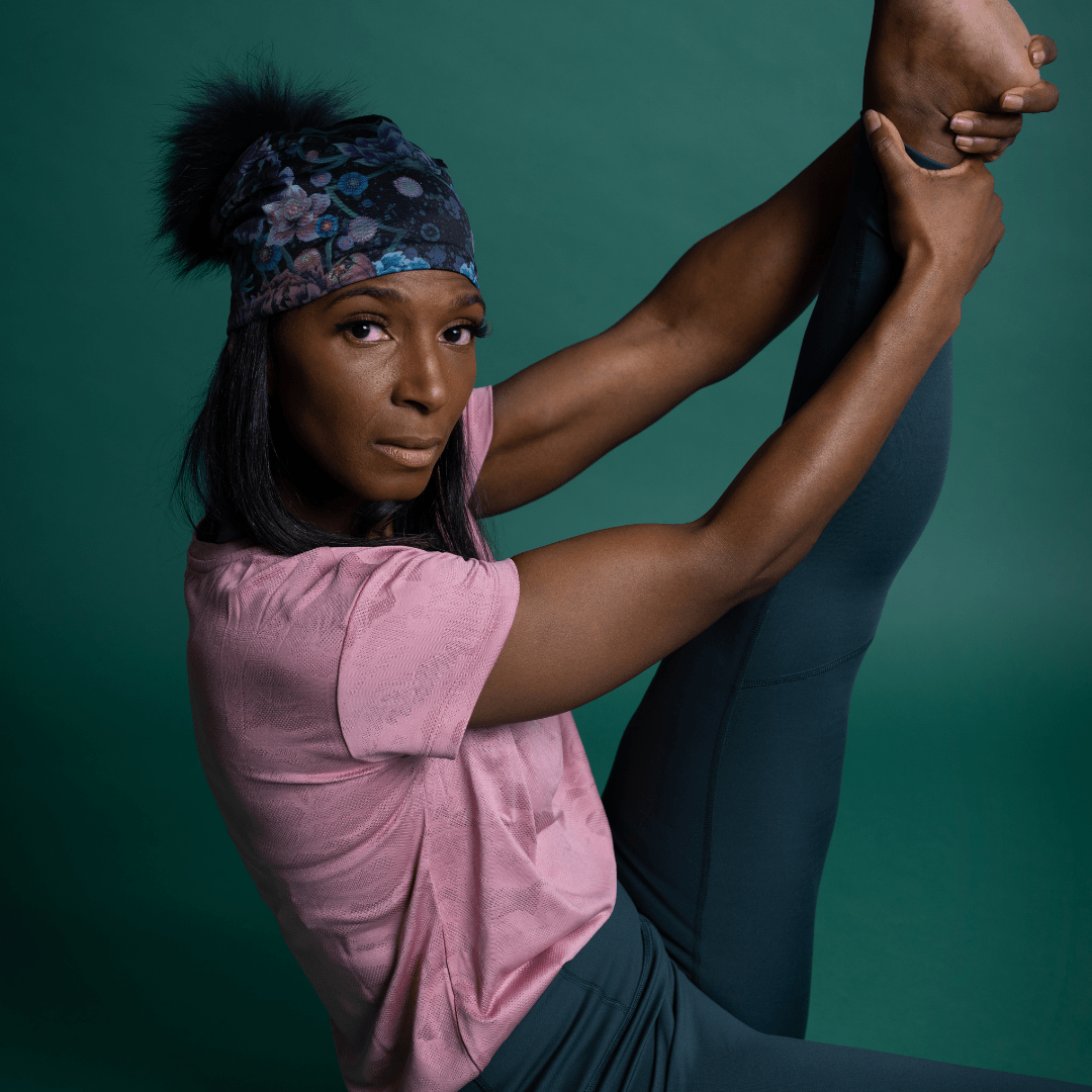 Gros plan sur une femme exécutant une pose de yoga difficile, portant la Tuque Pompon Flora.