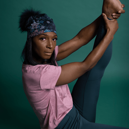 Gros plan sur une femme exécutant une pose de yoga difficile, portant la Tuque Pompon Flora.