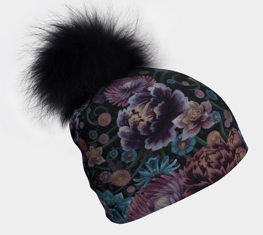 Tuque Pompon Flora avec un gros pompon noir et pelucheux et un motif floral éclatant sur fond sombre, vue de côté.