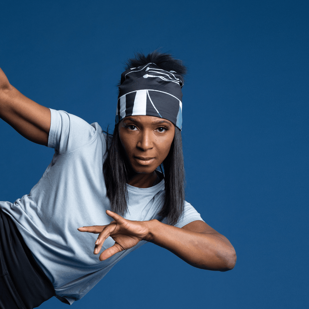 Femme portant la tuque à motif géométrique noir et gris comme bandeau lors d'une pose de danse.