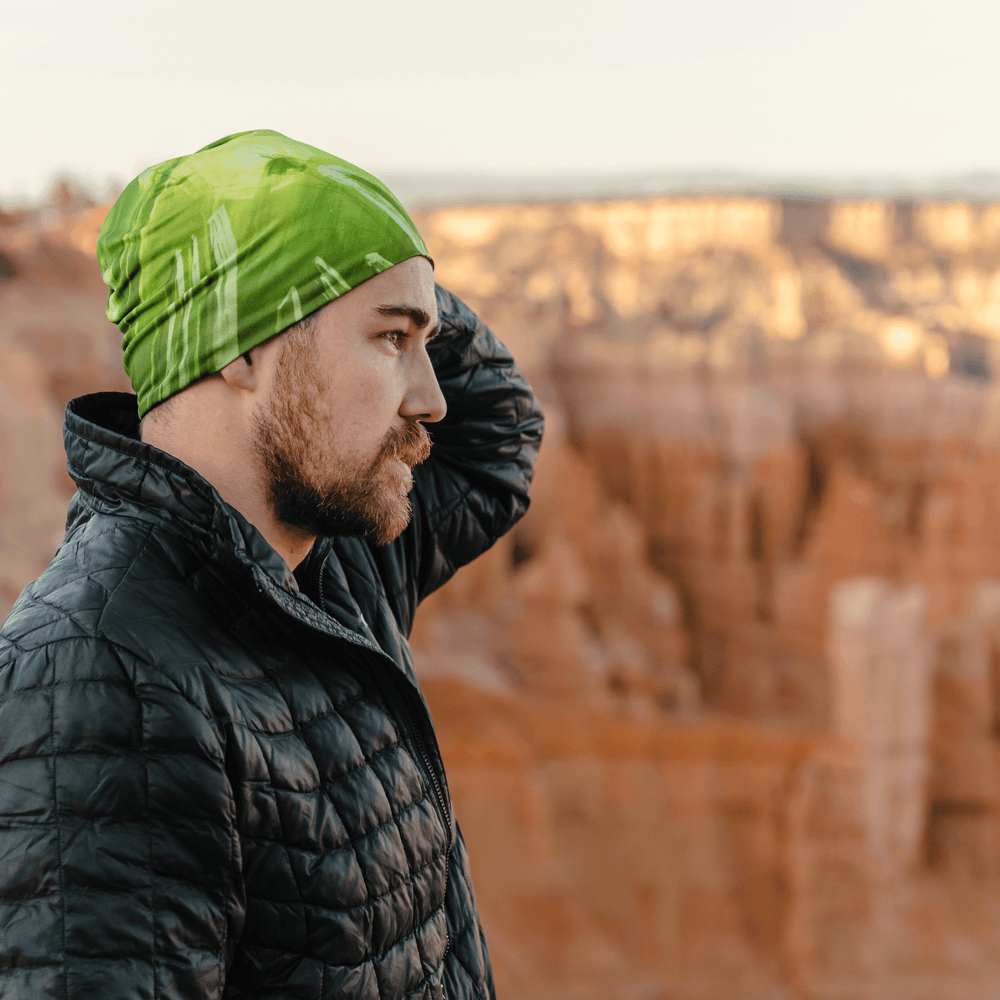 Homme portant la tuque sportive « Feu Vert » à l'extérieur, paysage de canyon rocheux en arrière-plan.