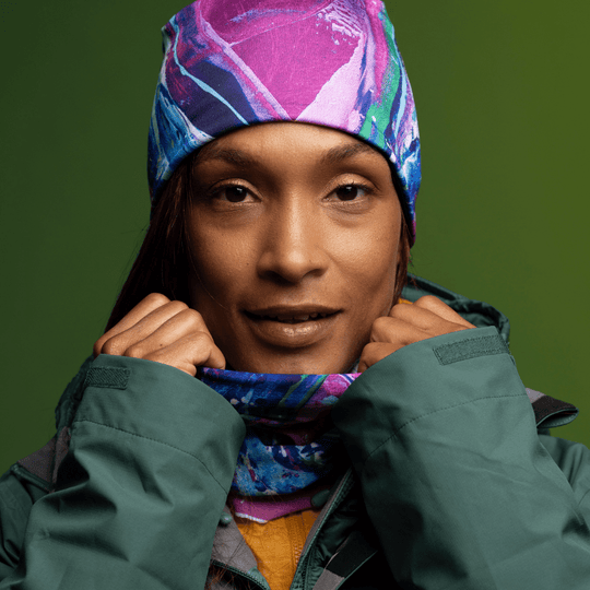 Close-up of a woman wearing the Hope tube as a beanie and neck gaiter, smiling at the camera.