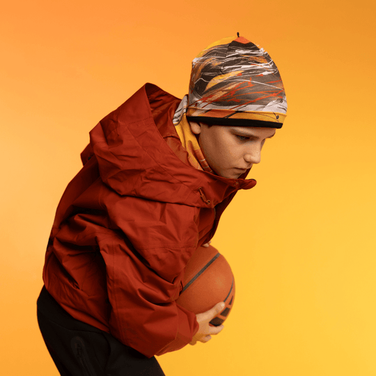 Young person wearing the Le Coeur Beanie and a red jacket, holding a basketball.