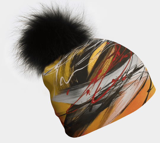 Le Coeur Beanie with a large black pom-pom, showcasing abstract yellow, black, and red art.
