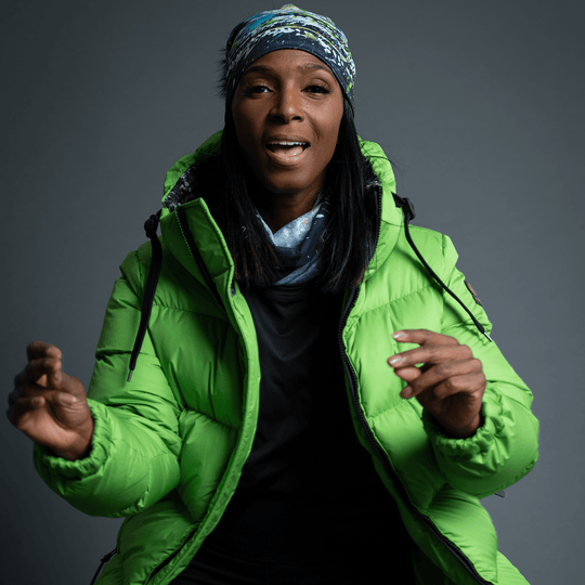 Femme portant la tuque Méduse en bandeau, souriante, dans une veste matelassée verte.