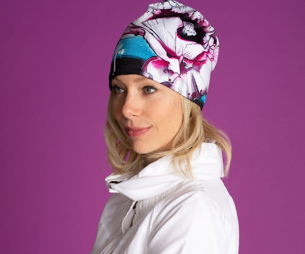 Femme portant la nouvelle tuque Fleur de pavot pour filles et femmes, mettant en valeur son design floral artistique sur fond violet.
