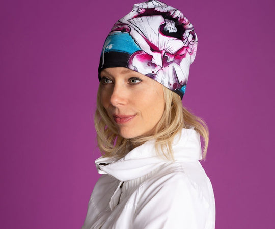 Femme portant la nouvelle tuque Pavot, qui présente un design floral coloré et un pompon noir.