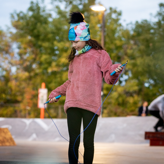Une jeune fille portant la tuque Fleurs Pastel en sautant à la corde à l&