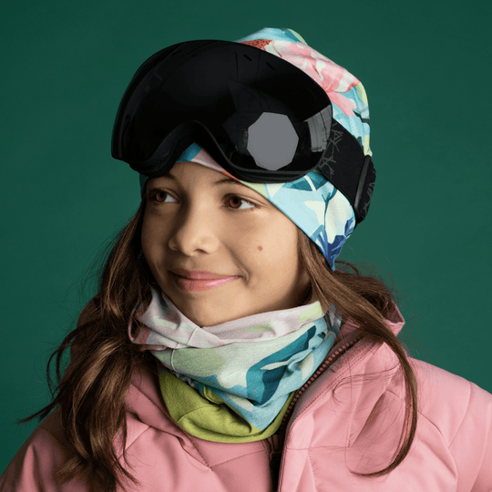 Jeune fille portant la tuque Fleurs Pastel et un cache-cou assorti avec des lunettes de ski.