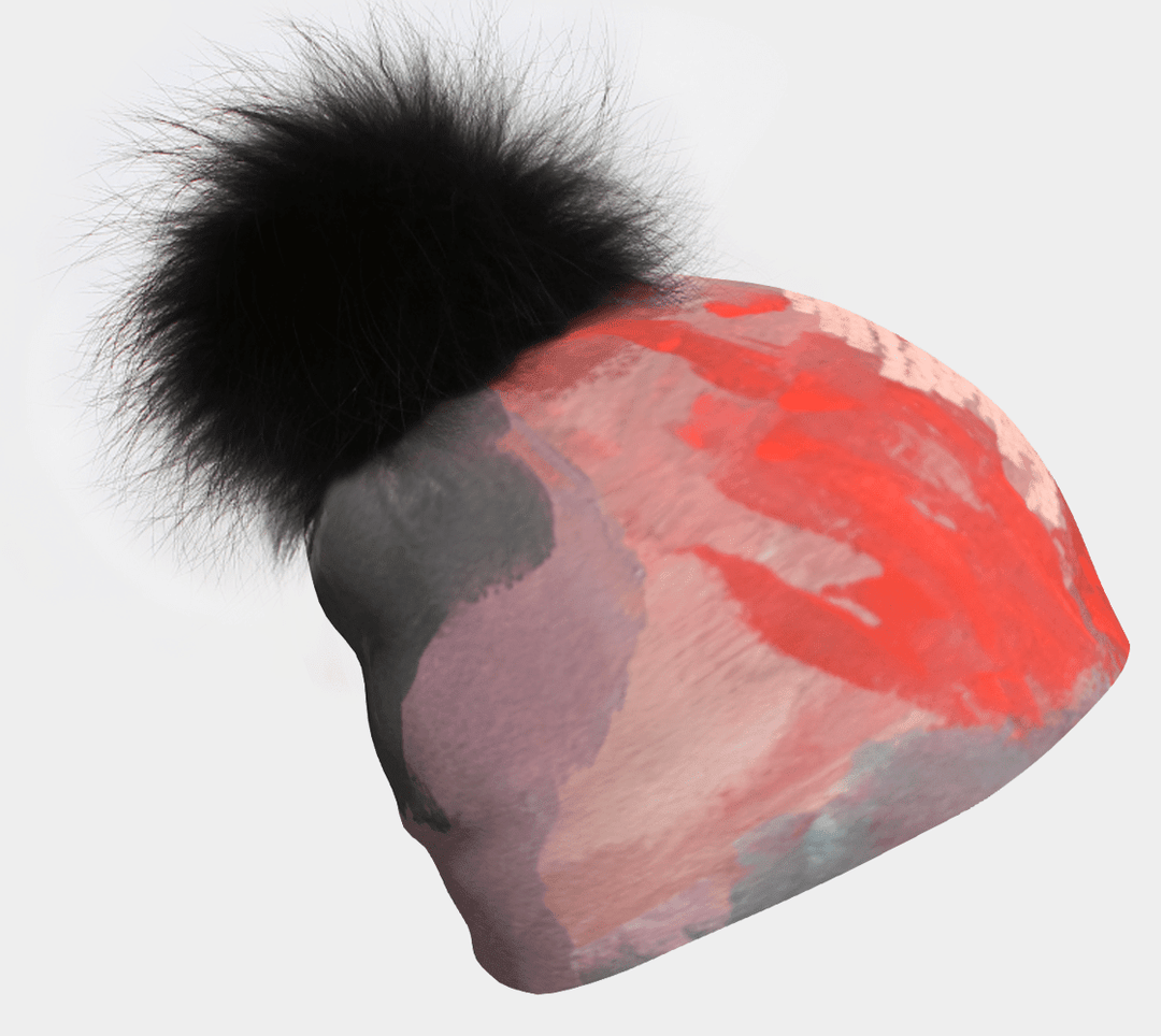 Beanie with a pink and orange abstract print and a black pompom.