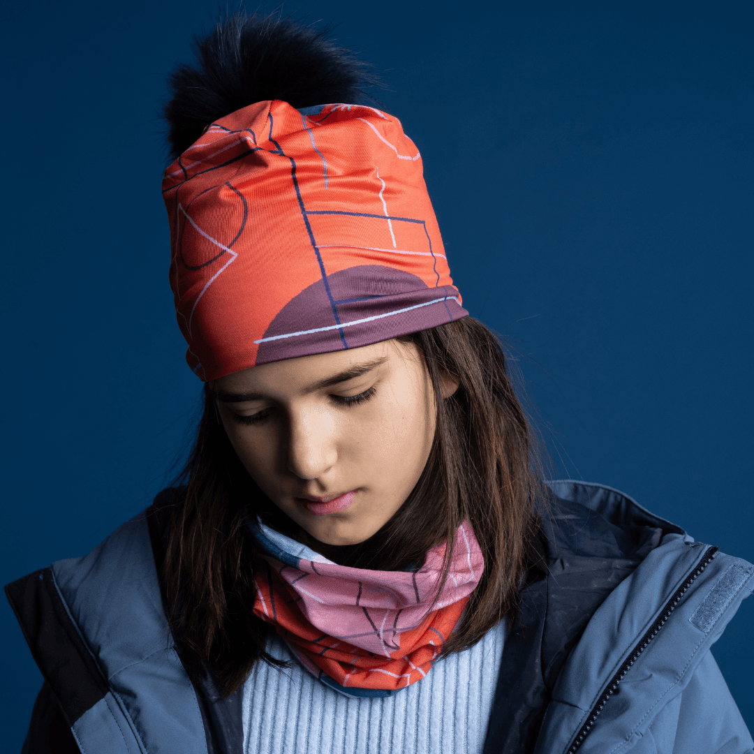 Une jeune fille portant la tuque Graphiques Roses et un cache-cou assorti, regardant vers le bas.