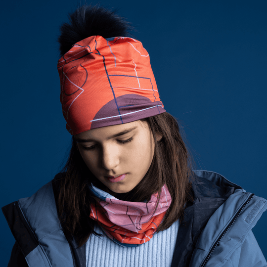 Une jeune fille portant la tuque Graphiques Roses et un cache-cou assorti, regardant vers le bas.