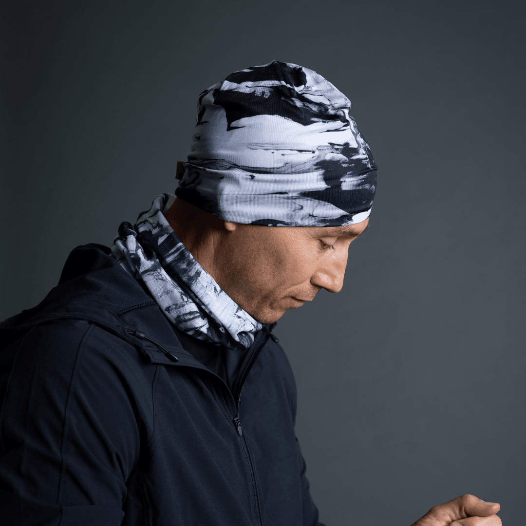 Man wearing the black and white abstract patterned tube as a beanie and neck gaiter with a dark jacket.