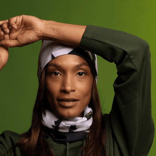 Woman wearing the POLAR Modern Quilt Multifunctional Tube as a beanie and neck scarf, styled with a green hoodie.