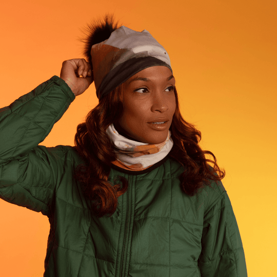 A woman wearing a green quilted jacket, with the POLAR Navy Accent Multifunctional Tube styled as a neck warmer, peeking out from her collar.