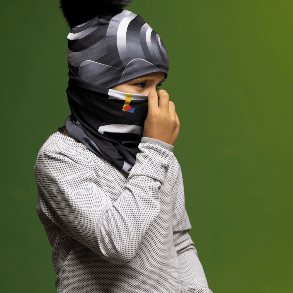 Enfant portant une chemise grise à motif gaufré et un tube de cou à imprimé abstrait noir et gris remonté comme cache-visage.