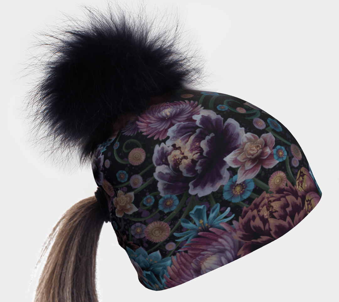 Ponytail Flora Pompom Beanie with a black fur pompom and a floral pattern, showing a ponytail emerging from the back.