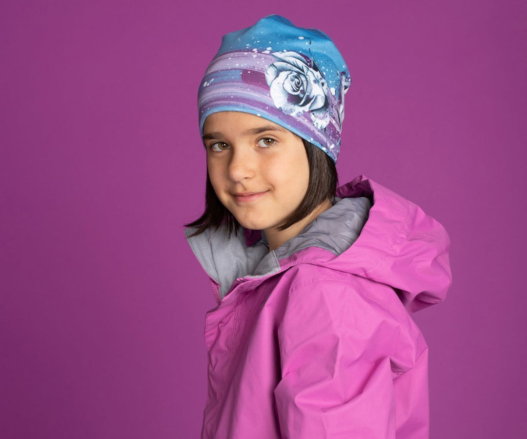 Une jeune fille en veste rose portant la tuque florale bleue Roses.