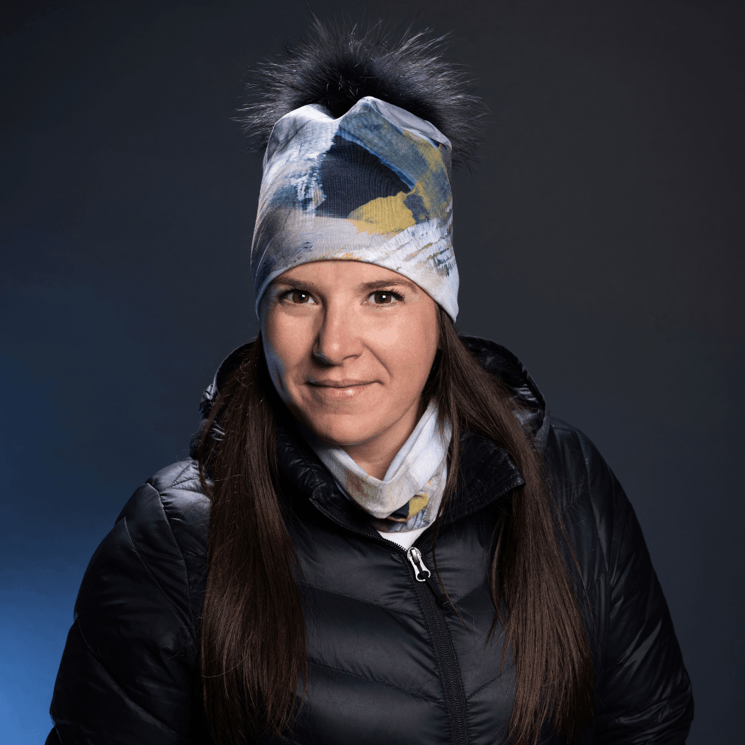 Femme portant la Tuque Sable avec Pompon Noir Amovible, souriante, sur fond sombre