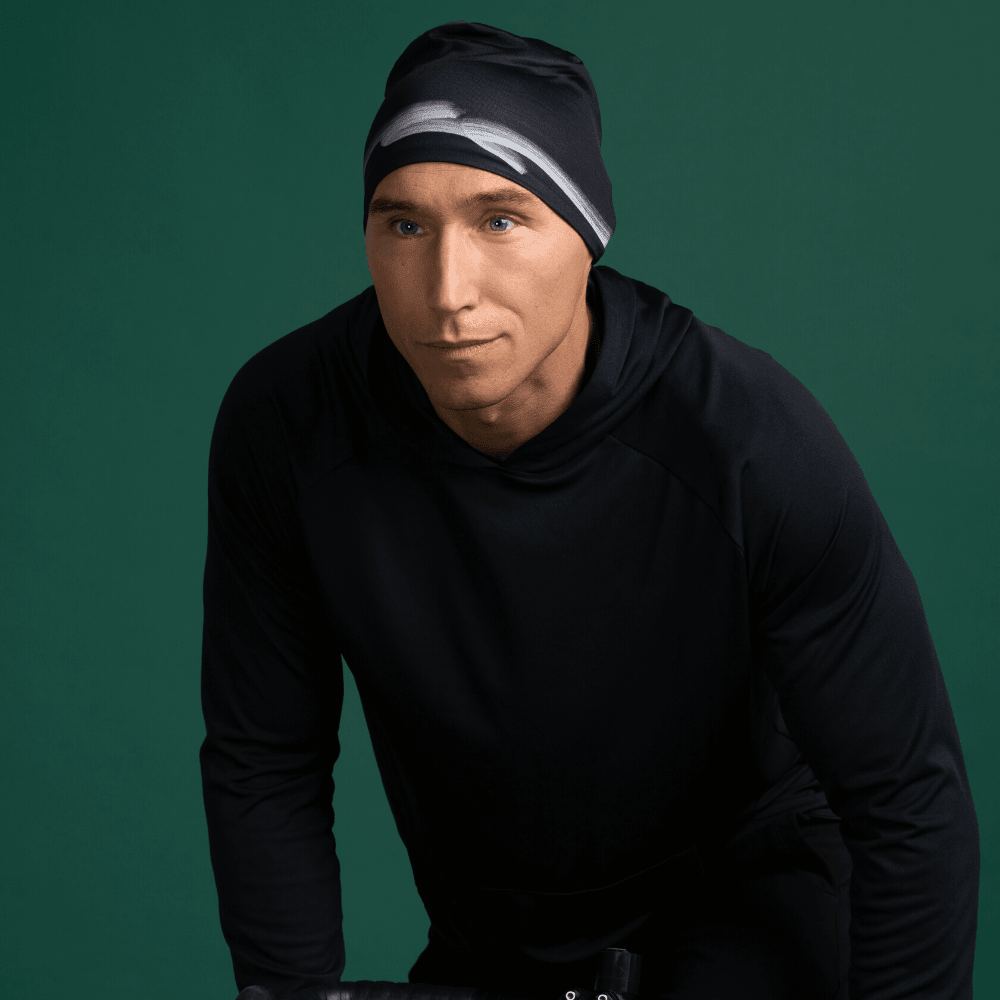 Homme portant une tuque noire et un sweat à capuche noir, regardant sur le côté.