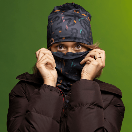 Woman wearing a brown puffer jacket and the Symetrick Gray Multifunctional Tube pulled up over her face.