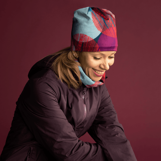 Femme portant la tuque Pois Bleu-Vert et un cache-cou assorti avec une veste violette.