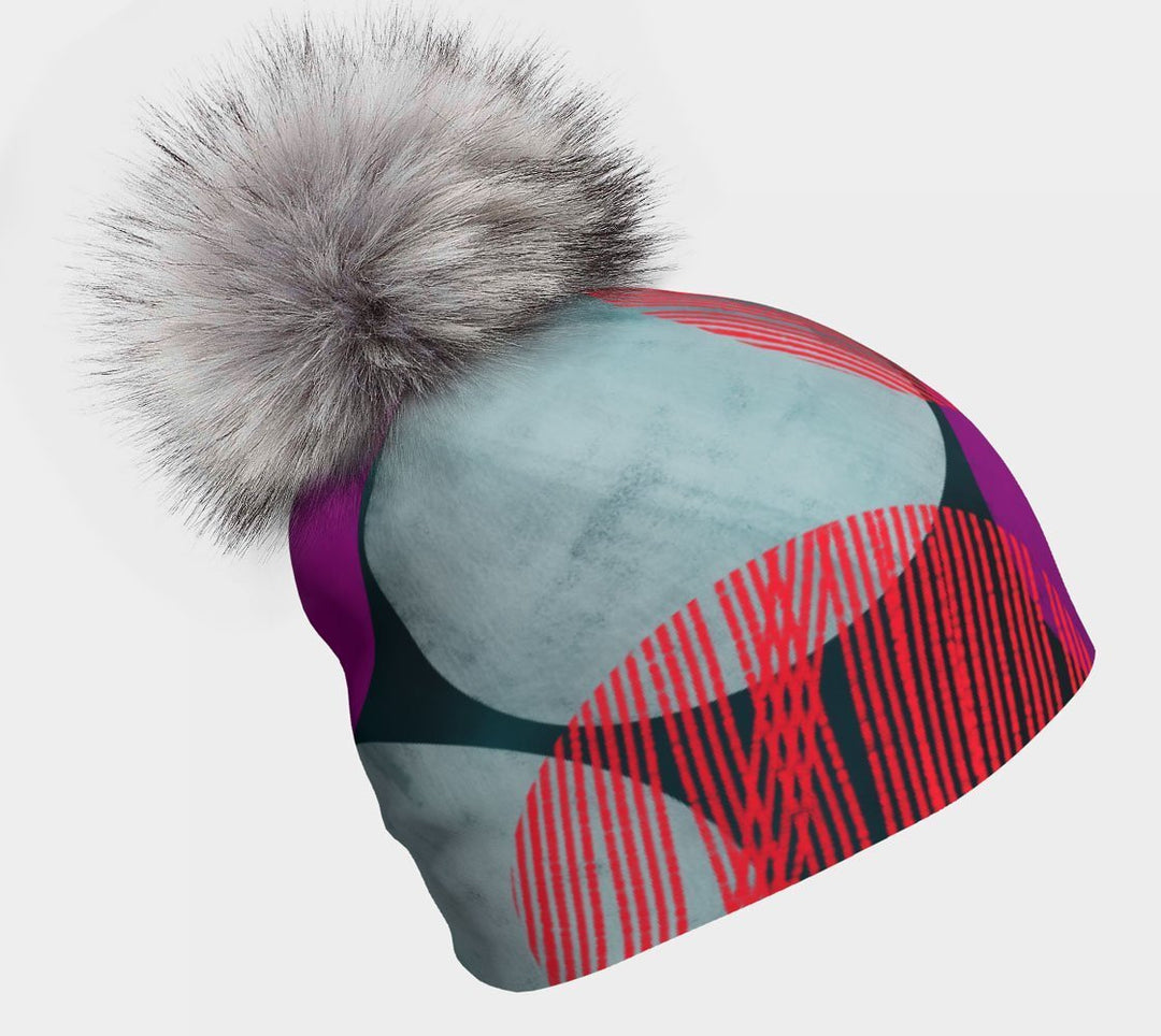 Tuque Pois-Bleu avec pompon gris détachable, ornée d'un grand pompon gris, sur fond neutre.