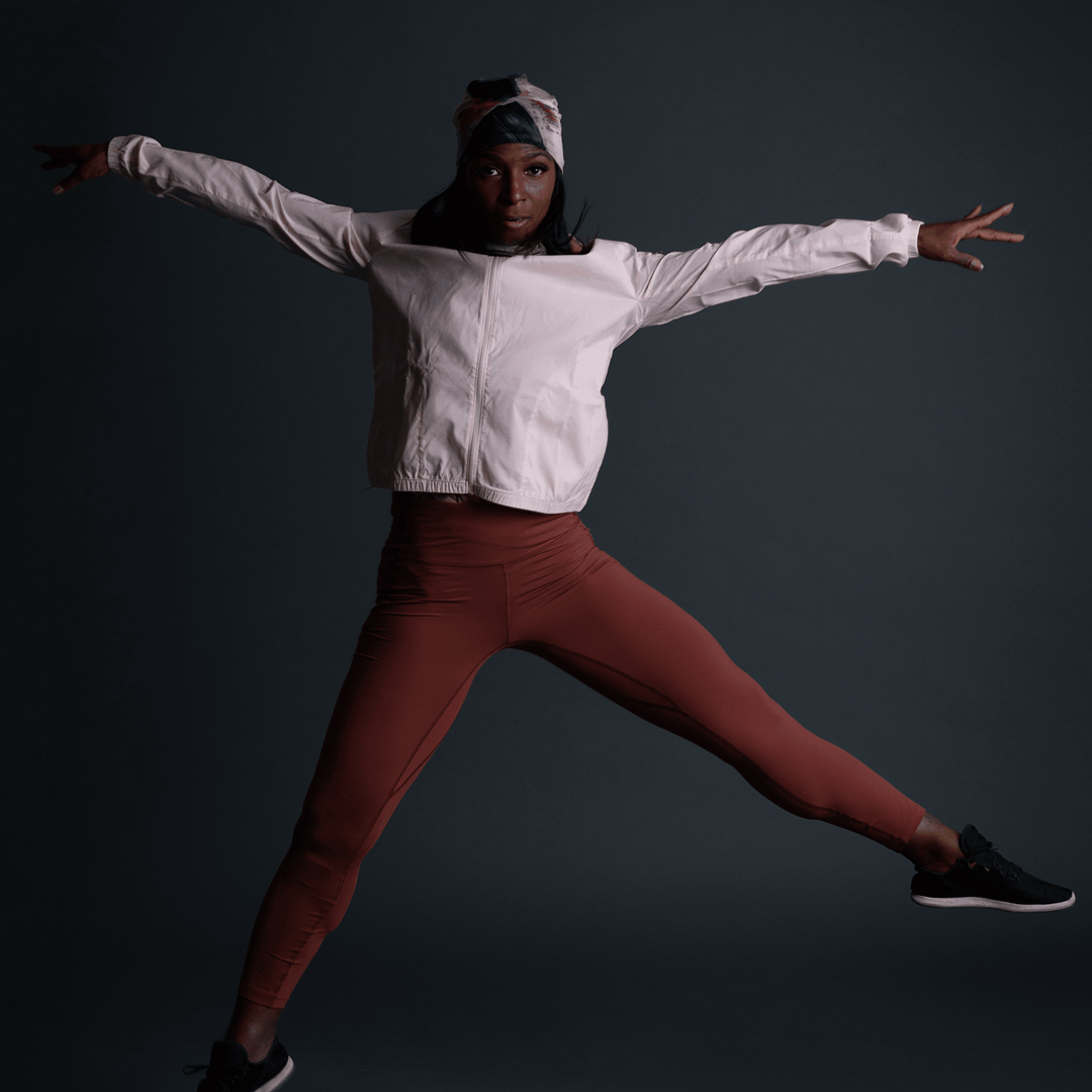 Femme en tenue sportive portant la Tuque Vie en Rose, capturée en plein saut.