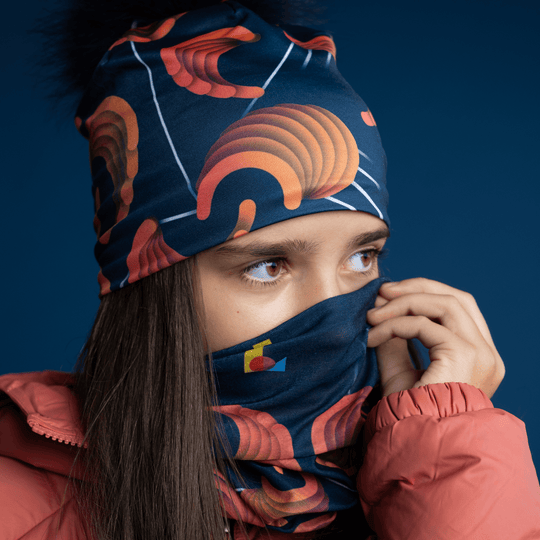 Jeune fille remontant la tuque marine avec motif abstrait sur son nez, avec un cache-cou assorti visible