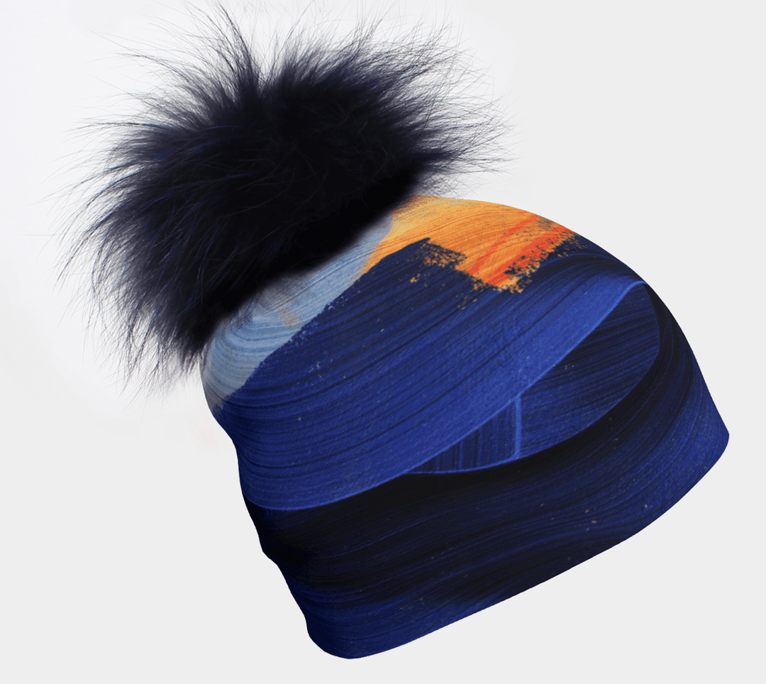Tuque jaune et bleue avec pompon en fausse fourrure marine amovible, présentant un art abstrait de coups de pinceau.