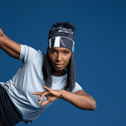 Woman in movement doing sport/yoga. The lady is wearing the sports cap called Geometrics designed by Valery Goulet. This active beanie hat is black and grey with a black pom-pom.