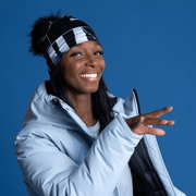 Woman in motion with her arm raised and her hand in the foreground. The lady is wearing the sports cap called Geometrics designed by Valery Goulet. This active 4 season  beanie is black and grey with a black pom-pom.