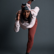 Woman in front running and is in motion. The woman is wearing a 4 seasons yoga hat designed by Catherine Parent. The hat is colored in pink, grey and beige tones, and has a black pompom. 