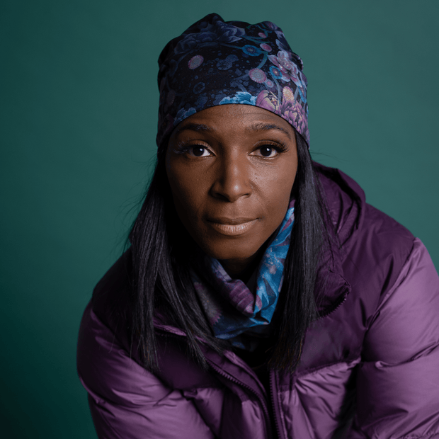 Woman wearing the perfect accessories duo to enjoy outdoor activities with the dark Purple and Blue Flora Beanie and polar tube illustrated by Claire Anghinolfi for Lalita's Art Shop.