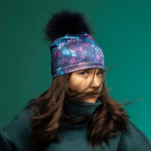 Teenager girl wearing the floral Blue and Purple Wisteria Beanie with Navy Pompom by Claire Anghinolfi for the Lalita's Art Shop 24 collection